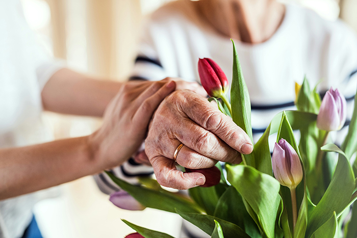 Image of elderly woman's hand arranging flowers